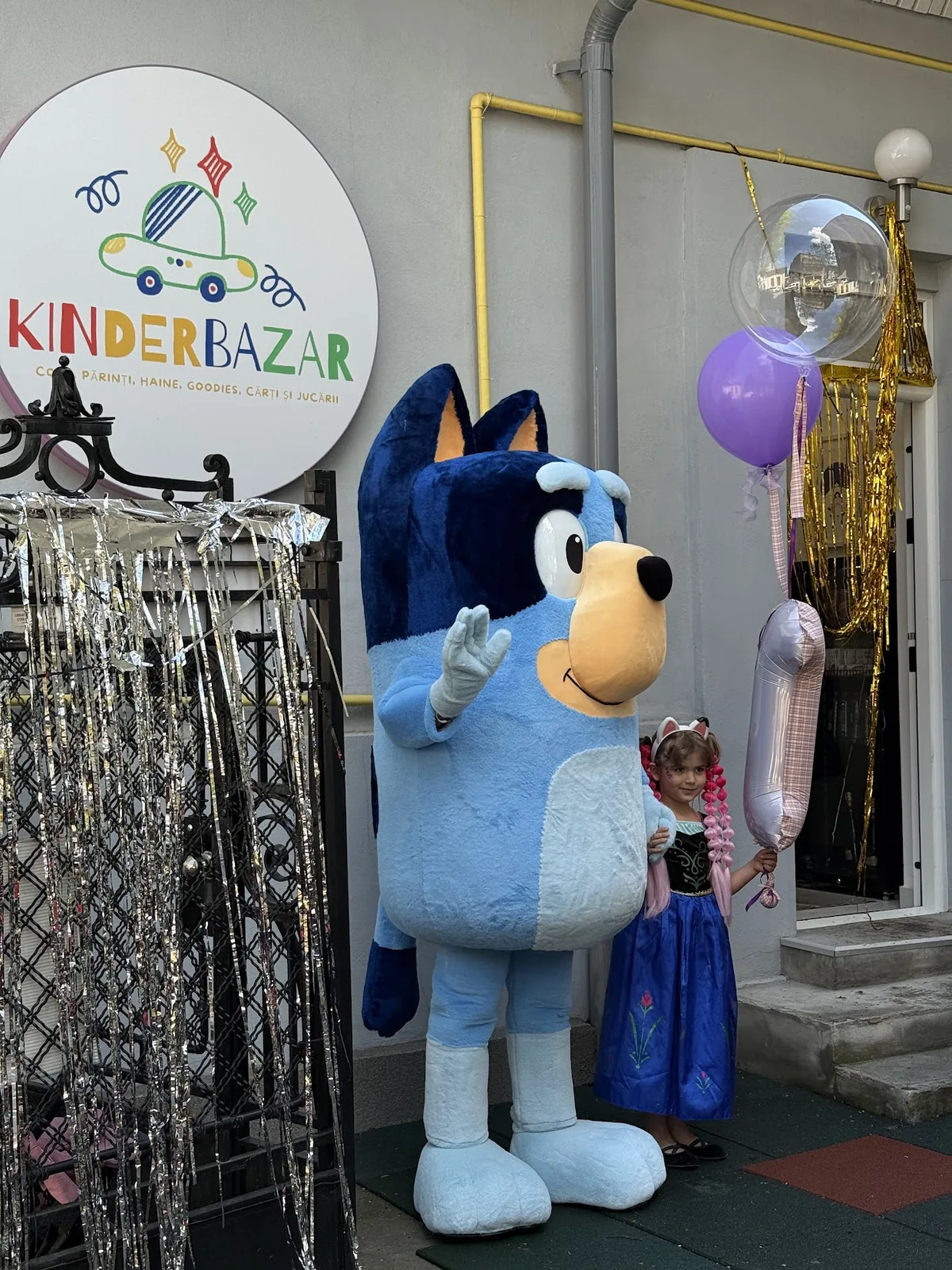 Mascotă și copil în fața magazinului Kinderbazar