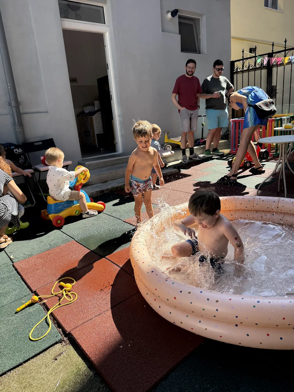 Copii jucându-se cu apă în curtea Kinderbazar